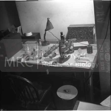 A desk in Rosalind Franklin's laboratory at 21 Torrington Square, London (part of Birkbeck College), showing her microscope and other equipment. Photographed by John Finch shortly after Franklin's death in 1958. More photographs from this series can be seen at the Models & Artefacts section of the website.