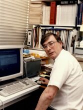 Bart Barrell, sat in front of a computer, c.1990s