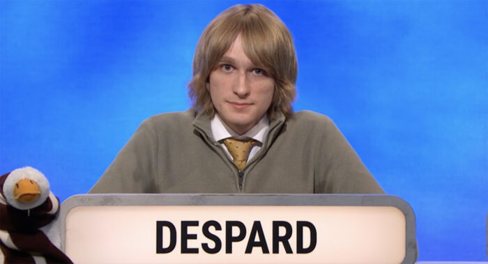 Oscar Depard sits behind a lit sign reading his surname in capital letters. To his right is a stuffed goose, the team’s mascot.