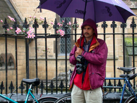 Neil Grant holding a purple umbrella and a camera, 2003