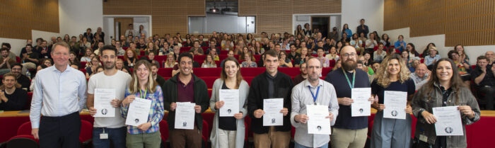 LMB prize winners with certificates in the Max Perutz Lecture Theatre with clapping audience