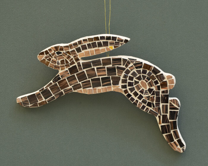 A profile view of a rabbit in motion, with mosaic tiles following the contour of the animal's shape. 