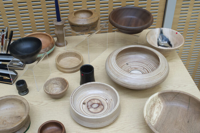 Various items displayed on a table which have been produced via wood-turning. These include a variety of bowls and dishes in different types of wood.