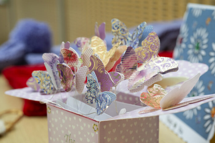 Close up of a card designed like a box with butterflies on wire coming out of the top. The butterflies are created with different coloured and patterned card.