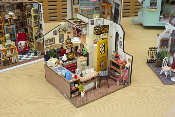 Several miniature model rooms displayed on a table. One in the foreground is of a kitchen space.