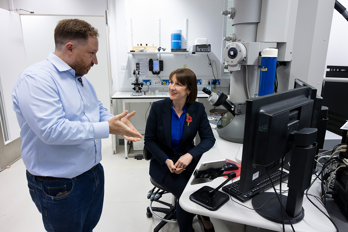 Chris Russo explains electron microscopy to The Chancellor Rachel Reeves, who is sat in front of an electron microscope